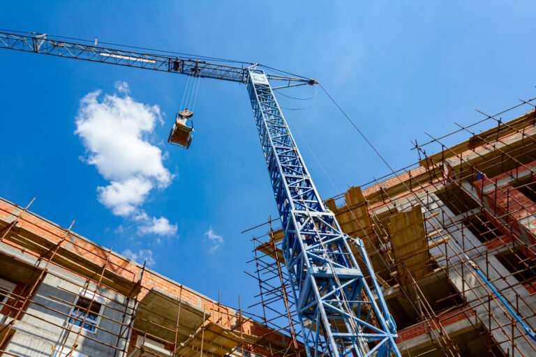Crane is lowering cart full of crumpled foil to the ground, industry trash, construction site works