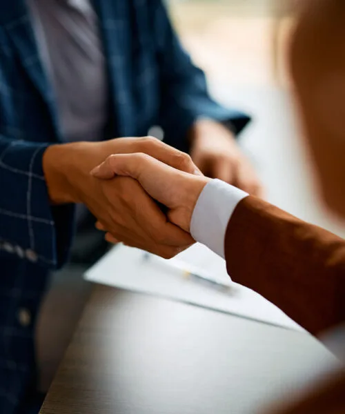 Close up of business people shaking hands in the office.